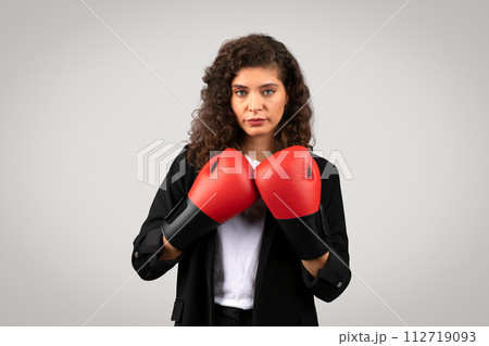 Determined businesswoman with red boxing gloves 112719093