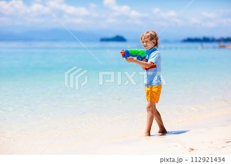 Child with toy water gun. Kids vacation beach fun. 112921434