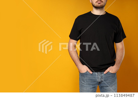 A young guy in a black T-shirt on a yellow background 113849487