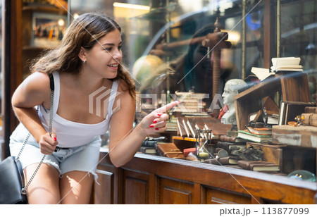 Interested young woman viewing retro-style stationery in souvenir store 113877099