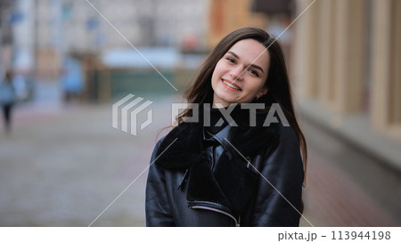 Happy brunette girl posing in black jacket in autumn in the city. 113944198