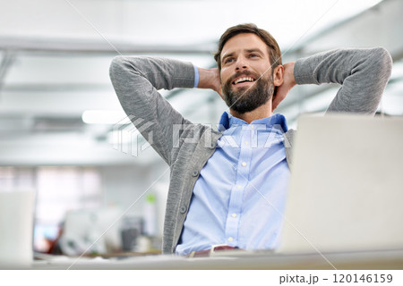 Taking a moment to think. Shot of a young businessman working on his laptop in the office and leaning back in his chair. 120146159