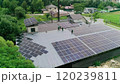 New solar farm under the blue sky. Workers in special outfit walk and talk about sunny cells installation. Modern solar panels produce clean electricity. Technicians installing solar panels. 120239811