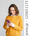 Smiling Woman Using Smartphone. A joyful young woman with curly hair using a smartphone. Ideal for 120651175