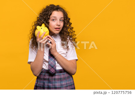 Curious girl listening to yellow piggy bank 120775756