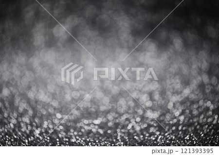 A bokeh background in black and white tones with small particles shining through. 121393395