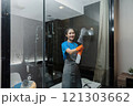 Cleaning online service. yong woman housekeeper cleaning bathroom mirror with cloth. House cleaning service concept 121303662