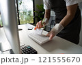 Person Cleaning Computer Keyboard with Brush in Modern Office Environment for Hygiene and Maintenance 121555670