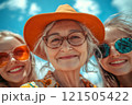 Gray-haired grandmother in a hat and two granddaughters 121505422