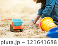 Little cute toddler boy 3.5 years old plays in the sandbox on a sunny spring day. Outdoor creative activities for kids. Toy truck and bucket. Focus on the car 121641688