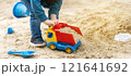 Little cute toddler boy three years old plays in the sandbox on a spring day. Outdoor development activities for kids. Toy cars and shovel. Focus on the car 121641692