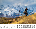 Photographer capturing snow covered mountains with professional camera equipment 121685819