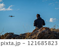 Drone pilot operating on rocky terrain during sunny weather outdoors 121685823