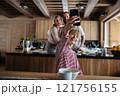 Girl is sitting at the table videocalling with grandparents. Morning routine for family. 121756155