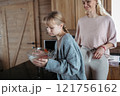 Mom and daughter making pancakes for breakfast. Girl mixing, preparing pancake batter in the kitchen. 121756162