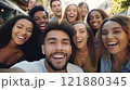 A joyful group of friends from different backgrounds laughing and taking a selfie together in a 121880345