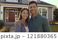 A young couple proudly holds up their new home keys outside their newly purchased house. They are 121880365