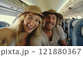 A couple smiles and poses for a photo on an airplane. The woman wears a stylish hat while the man is 121880367