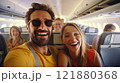 A joyful couple smiles at the camera while seated on an airplane. The man in a yellow shirt and 121880368