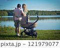 Young couple walking with newborn baby in stroller on lake 121979077