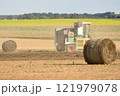 A tractor cleans the field with flax and makes bales 121979078