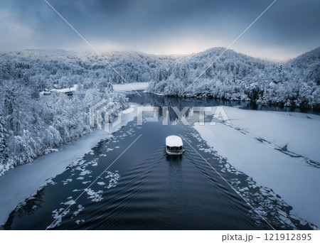 Aerial drone view of boat in frozen lake at sunset in winter 121912895