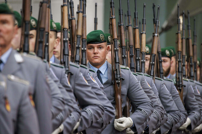 Soldaten vom Wachbataillon in Reihe, fokusiert auf einen sehr ernsten und seriös dreinblickenden Soldaten.