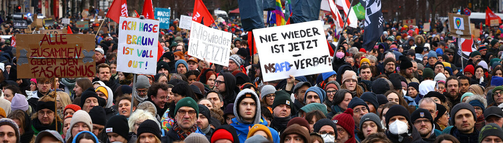 Menschen stehen dicht gedrängt mit Protestplakaten gegen die AfD auf der Straße