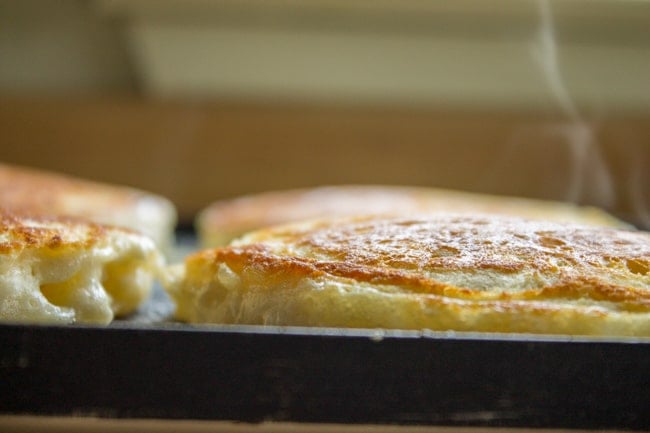 Fresh fluffy pancakes with crispy edges cooking on a griddle.