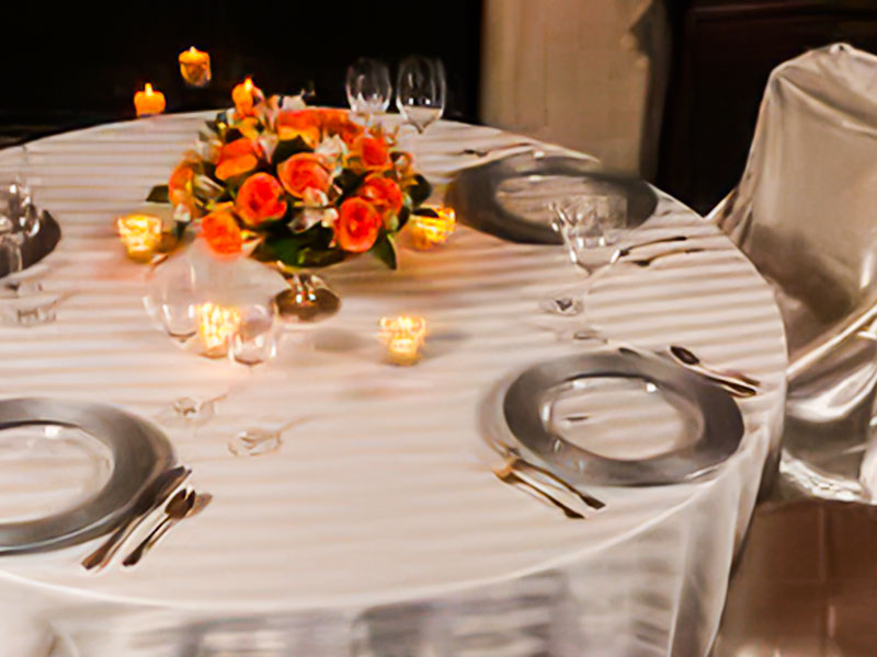 Silver and white striped imperial linen on a table with place setting and canals and a flower centerpiece.