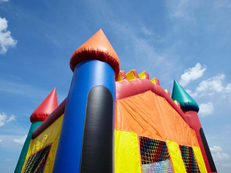 Children's inflatable bouncy castle with a blue sky and clouds.