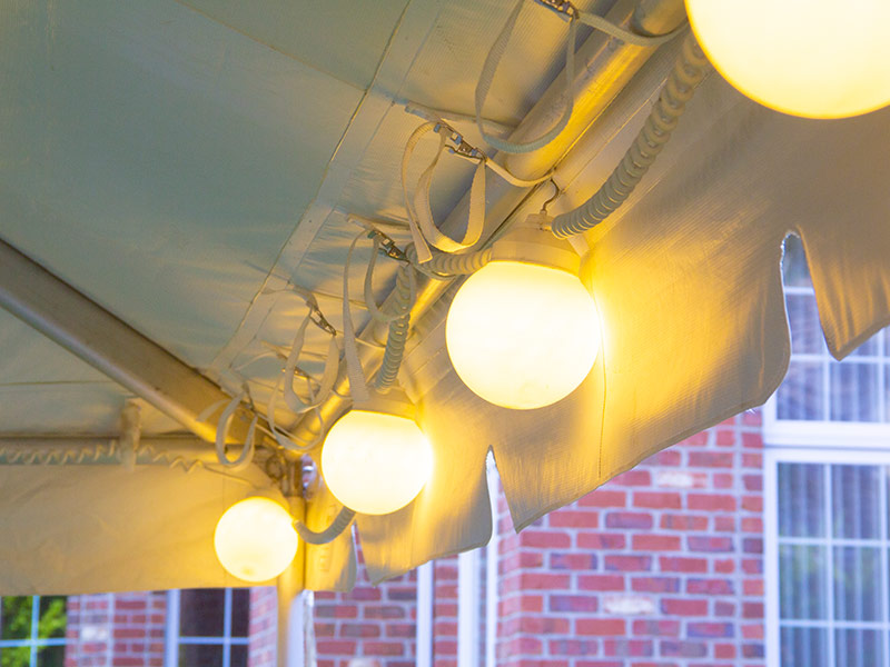 Globe lights hung on the inside perimeter of a frame tent.