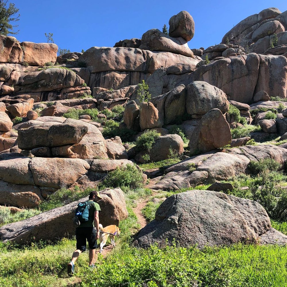 A man and his dog walking through the rock formations of Vedauwoo, a unique place to visit in Wyoming.