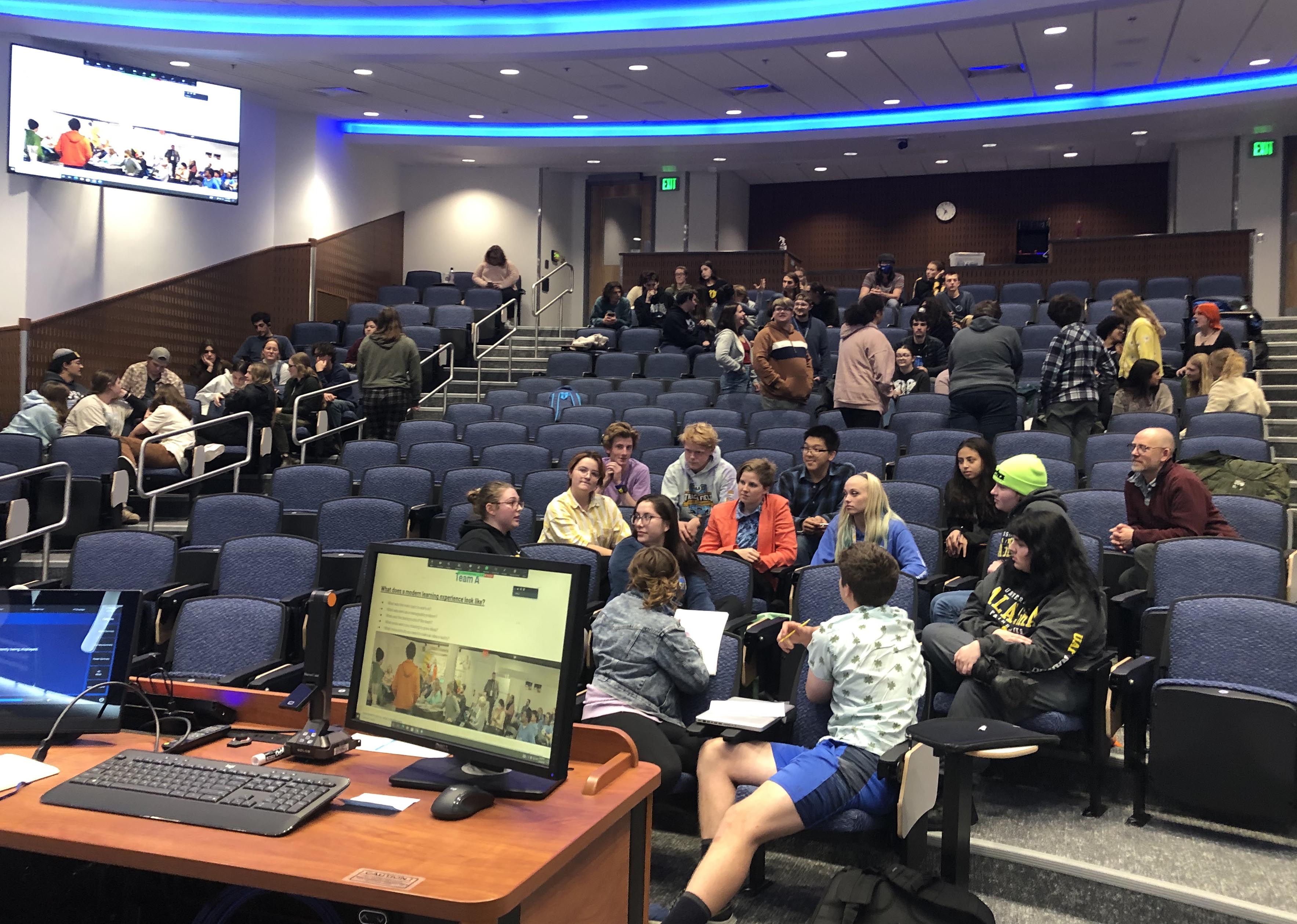 Students cluster in groups to talk in an auditorium