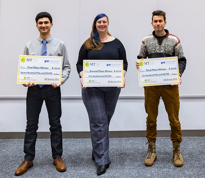 Three students stand with checks for their wins in the UAF Three Minute Thesis competition.