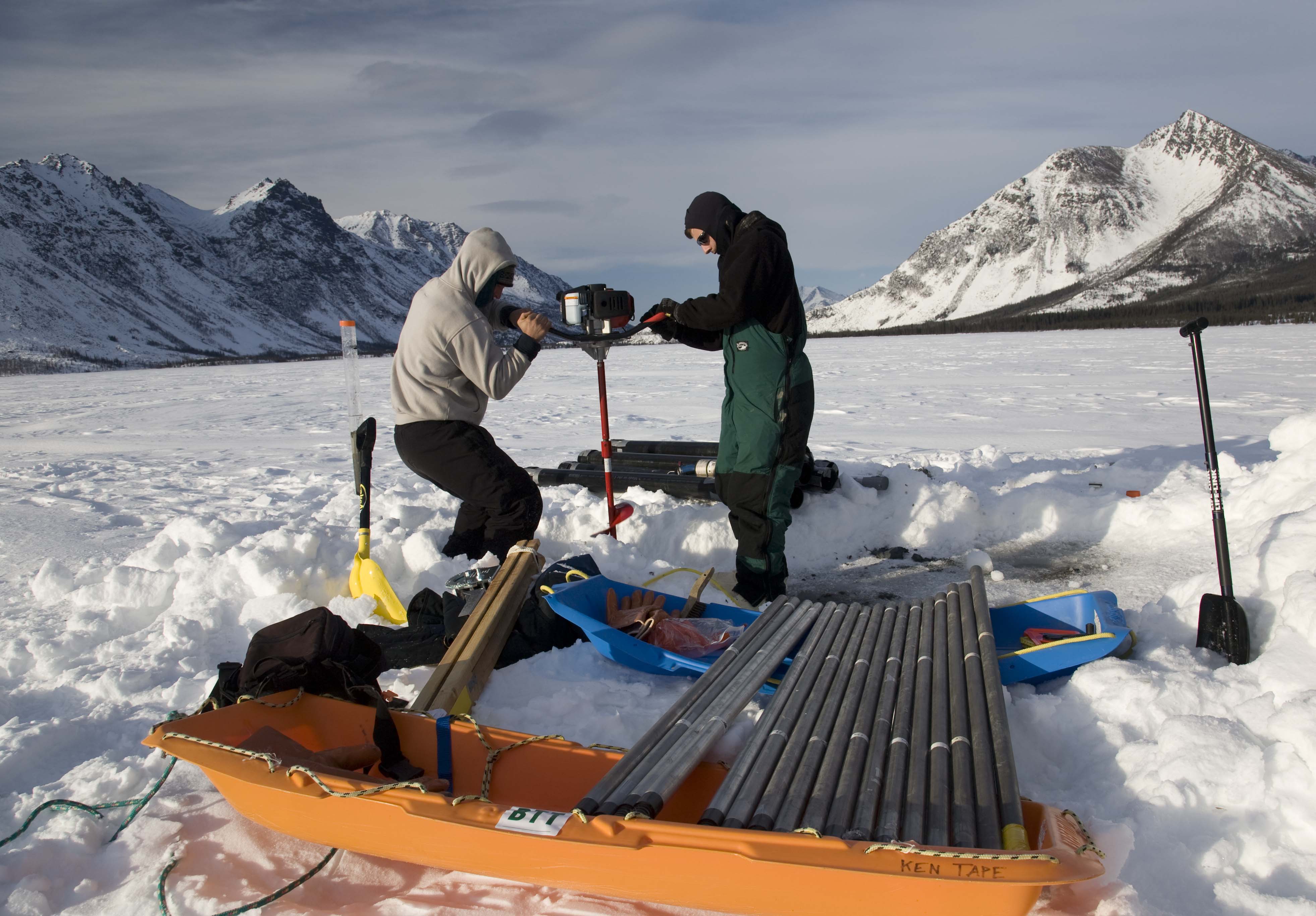 Students drill into ice as they perform research in the field.