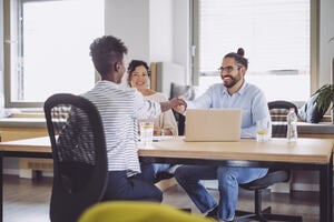 Three people sat at a desk having a conversation.