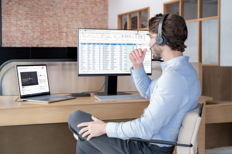 Young man wearing headset working on Laptop 6 linked to big screen