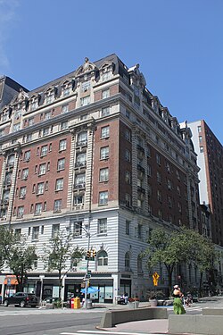 View of the Marseilles from the intersection of Broadway and 103th Street. The facade is largely made of red brick, except at the base, where it is made of stone. The top of the hotel contains windows within a black mansard roof.