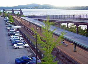 A covered railway station platform with two tracks next to a wide river