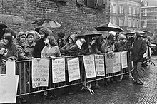 About thirty demonstrators stand behind crowd barriers in the Binnenhof while it is raining. Banners read, among other things, "Don't let the woman end up with the bill" and "No compromises, the woman should decide."