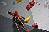 A climber using one-finger pockets on an overhanging limestone rock face