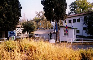 Photo du camp argentin des forces de l'ONU avec un checkpoint militaire et les drapeaux de certains des pays participant à la mission d'interposition.