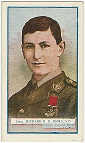 Head and shoulders of a young British officer. He is Caucasian with brown hair that is parted to the right. He is wearing a military uniform with the Victoria Cross pinned to the left breast.