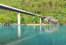 Weitaufnahme des Goldswil-Viadukts vom Ufer der tiefblauen Aare aus.