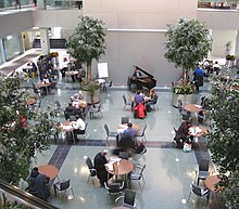 Interior of the tower's public lobby, which contains trees, tables, and chairs