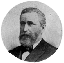 A black and white circular portrait of a Caucasian man in a suit and bow tie