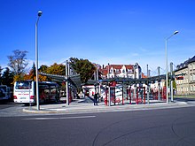 Barevná fotografie s pohledem na nástupiště autobusové nádraží uprostřed města