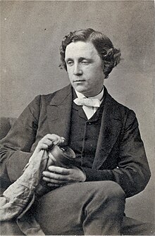 tinted monochrome 3/4-length photo portrait of seated Dodgson holding a book