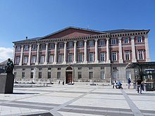 Photographie en couleur d'une place publique avec un bâtiment.